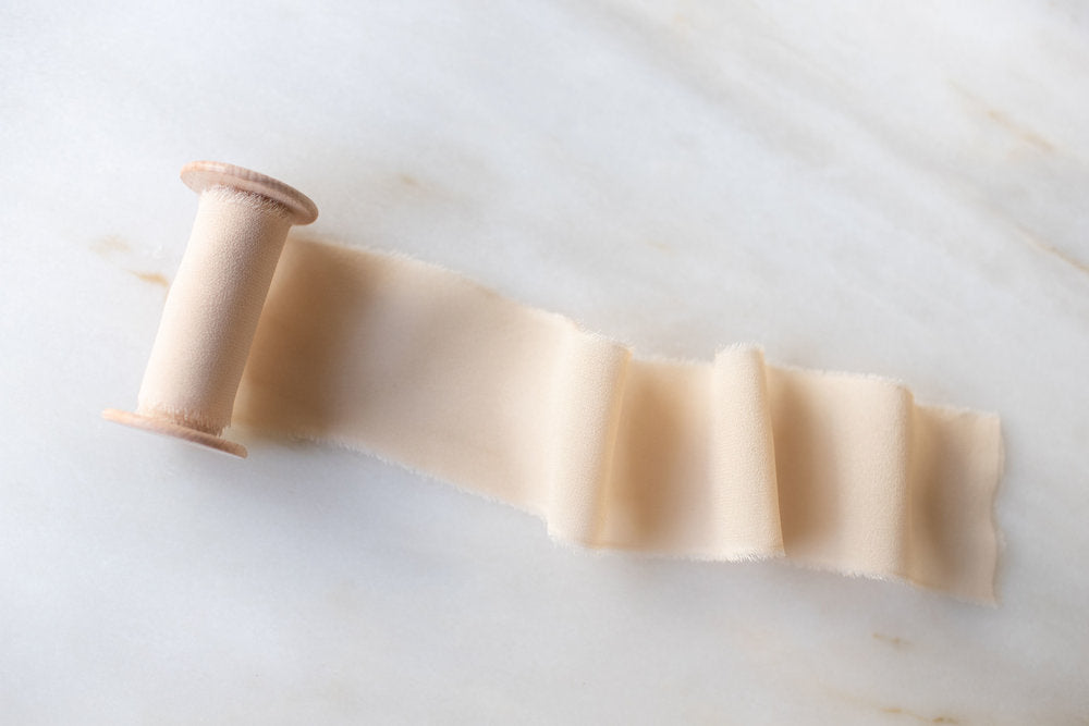 handmade and hand dyed creamy creme brulee silk chiffon ribbon on a wooden spool