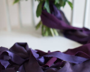 rich purple and violet silk ribbon in the foreground and a beautiful wedding bouquet in the background