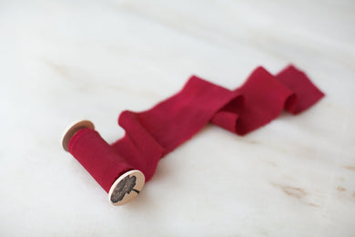 handmade crimson red silk ribbon on a wooden spool